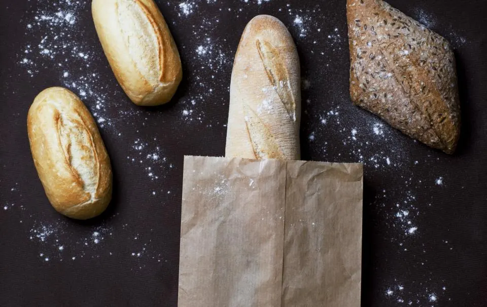 Fresh rolls and a baguette on a dark floured table