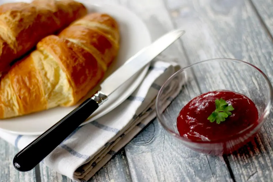 Golden croissants on a plate with a knife and jam